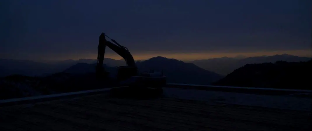A finished, freshly graded building pad at dusk with mountain ridges behind.