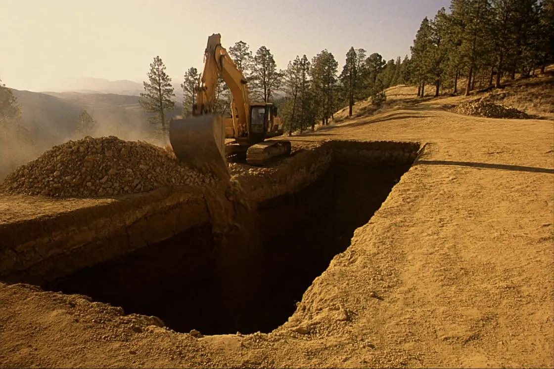 A deep foundation excavation with clean cut faces and a spoil pile alongside.