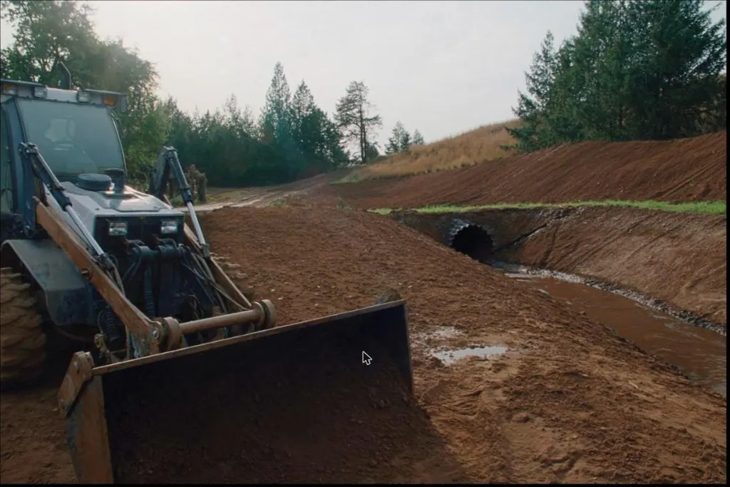 Finish grading work with a fresh drainage swale and a culvert set at a driveway approach.