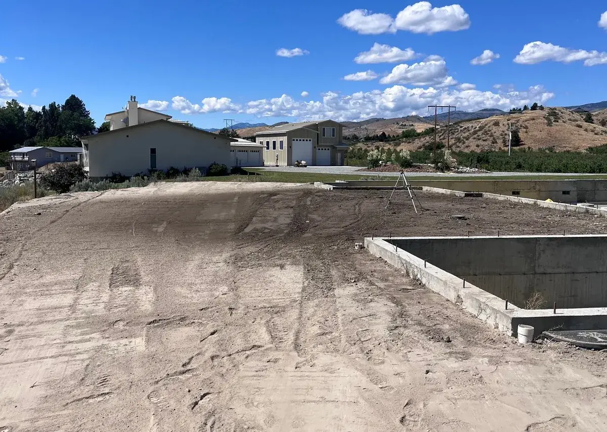 Finished foundation excavation, the pad cut and graded flat around the poured concrete footings